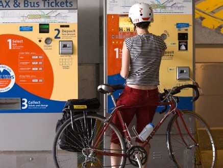 "A person buys a metro ticket while sitting on their bike."